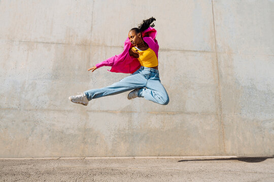 Young dancer hip hop dancing in front of wall