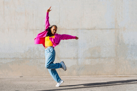 Dancer dancing with hand raised on footpath