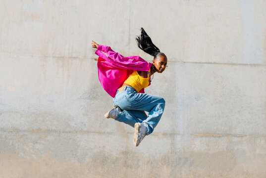 Young woman hip hop dancing in front of wall