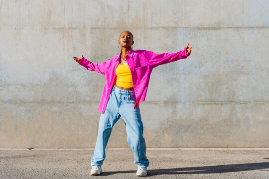 Young dancer with arms outstretched in front of wall