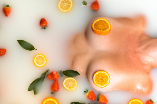 Anonymous woman covering nipples with orange slices