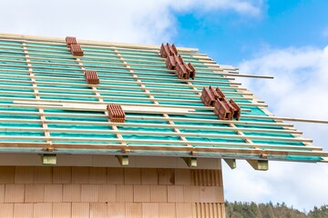 A roof under construction with stacks of roof tiles ready to fasten. Building a family house. Roof structure of the house.