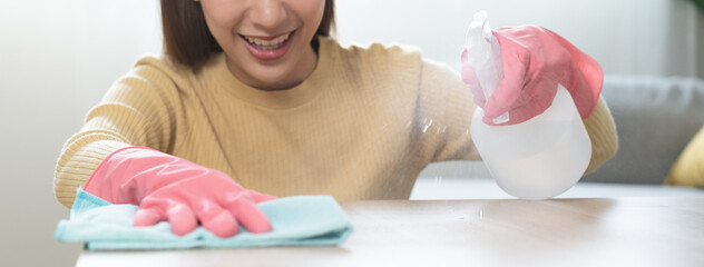Smile asian young woman, girl working chore, cleaning on table in house, hand using rag rub remove...