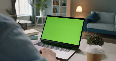 Close up shot of hands of a remote worker working on laptop computer with chroma key green screen, distance work, technology concept