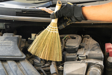 Cleaning dirty car engine bay with bamboo brush.