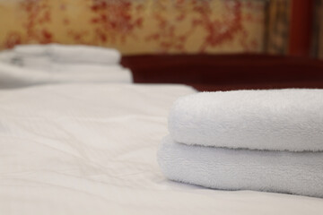 Fototapeta na wymiar Clean folded towels on bed in hotel room, closeup. Space for text