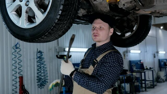 A male auto mechanic inspects a car, auto diagnostics in a car service. Car maintenance