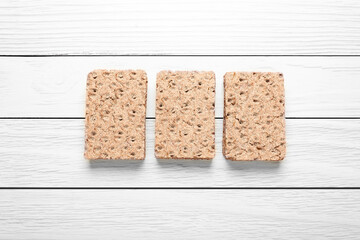 Tasty crispbreads on white wooden table, flat lay