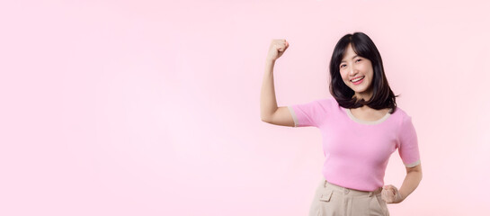 Portrait young asian woman proud and confident showing strong muscle strength arms flexed posing,...