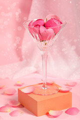 Martini glass with flowers and petals on pink background