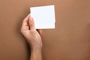 Man holding sheets of paper on brown background, closeup. Mockup for design