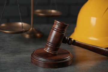 Labour, construction and land law concepts. Judge gavel, scales of justice with protective helmet on grey table, closeup