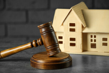 Construction and land law concepts. Judge gavel with house model on grey table, closeup
