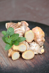 closeup the ripe sliced brown ginger with green mint on the wooden background.