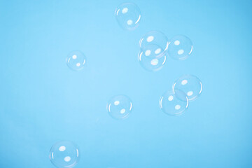 Many beautiful soap bubbles on light blue background