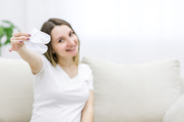 Blurred pregnant woman on background holding small white socks.