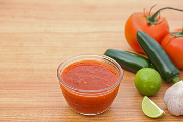 Tasty salsa sauce and different ingredients on wooden table. Space for text