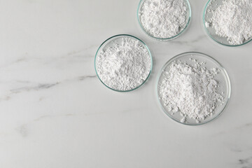 Many petri dishes with calcium carbonate powder on white marble table, flat lay. Space for text