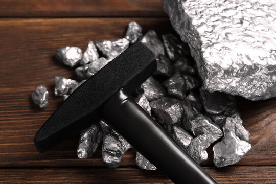 Pile of silver nuggets and hammer on wooden table, closeup
