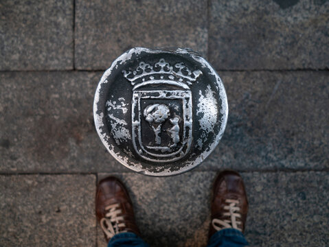 El escudo de la ciudad de Madrid es observado por un turista.