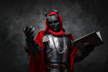 Shot of mysterious cultist dressed in steel armor and red mantle holding book.