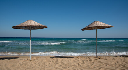 Beach umbrellas in the sandy coast beach against blue sky. Summer holidays in a resort