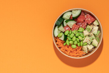 Poke bowl in cardboard containers on bright sunny background. Summer mood concept. Healthy food delivery