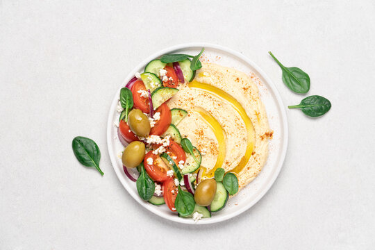 Hummus salad in plate on light background with copy space. Healthy food. Dip plate appetizer with greek salad