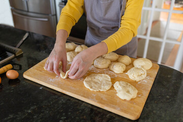 Woman making a bread  out of dough at home kitchen 