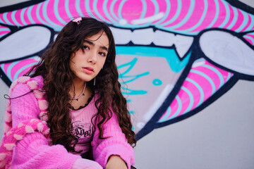 Portrait of teenage girl dressed in gothic style posing on a graffiti background