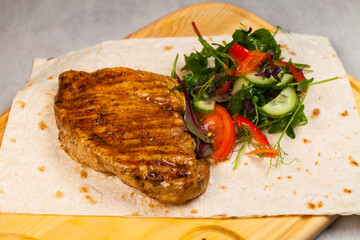 Chicken steak and salad on the wooden chop board.