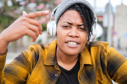 Close-up of young woman with her hair covered by a hat rapping outdoors and rhyming to music. Concept: Lifestyle, urban style, music