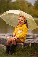 Happy little girl have a fun under umbrella in rain day