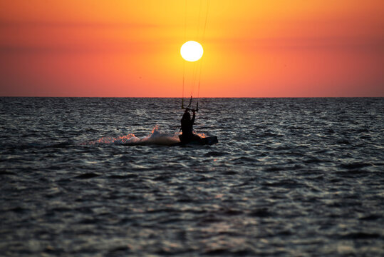 Silueta de mujer surfeando al atardecer en la r&iacute;a