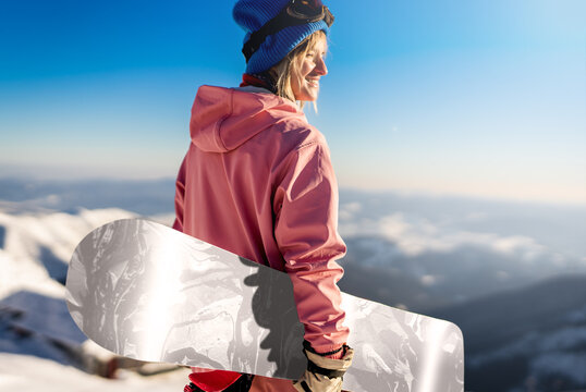 Girl snowboarder stands with snowboard on mountain's top