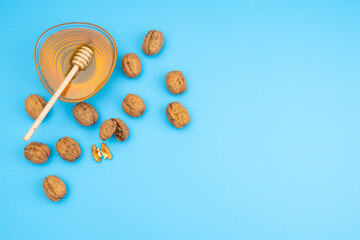 Bowl with honey, walnuts and pecans on a blue background as a concept of healthy eating, dieting and fasting