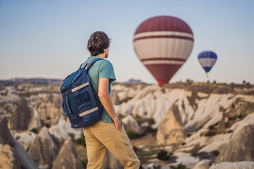 Tourist man looking at hot air balloons in Cappadocia, Turkey. Happy Travel in Turkey concept. Man on a mountain top enjoying wonderful view
