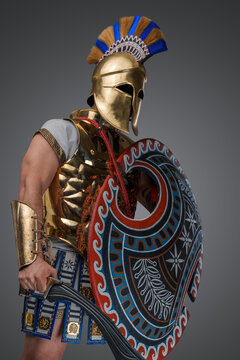 Studio shot of antique greek warrior with sword and shield against gray background.