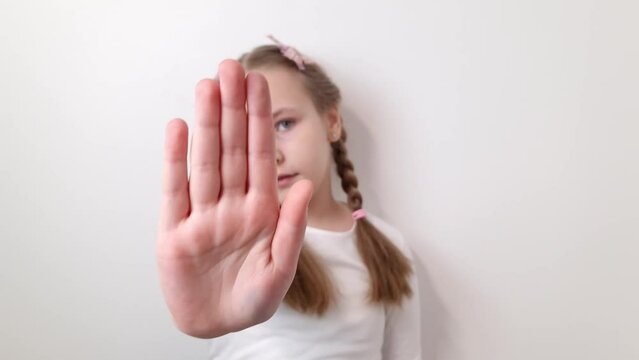 Little caucasian girl making stop sign gesture with hand. Children rights, violence, harassment concepts