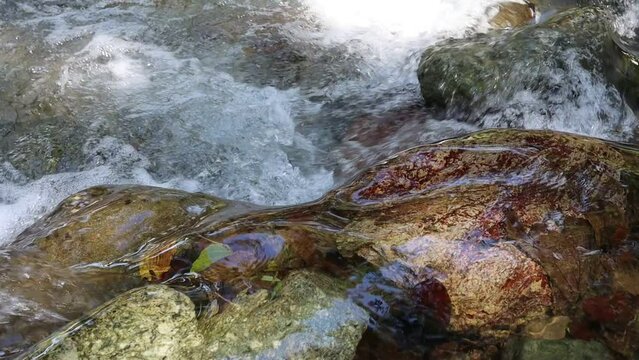 Agua fluyendo del manantial sobre las rocas en parque nacional en c&aacute;mara lenta. Concepto medioambiente.