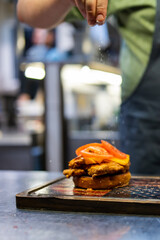 chef hand cooking chickenburger on restaurant kitchen