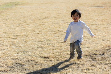 three year old mexican boy playing and running outdoors