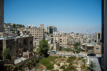 Fototapeta na wymiar Ramallah Cityscape Between Two Walls with High White Rock Buildings, Trees and Grass