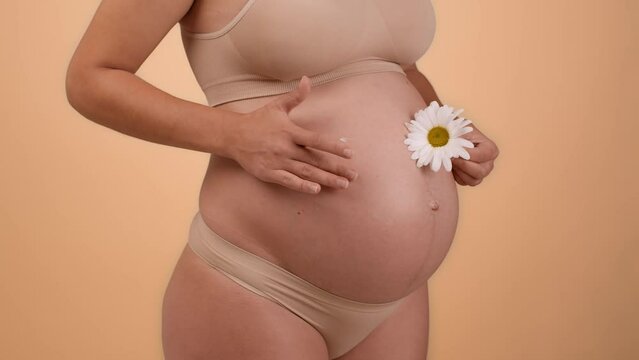 Natural cosmetics for expectant. Close up shot of unrecognizable pregnant woman pampering cream on her belly