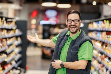 A friendly salesman welcoming customers in supermarket.