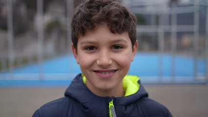Portrait of a happy handsome young boy standing outside. Closeup face of a smiling preteen male kid looking at camera © Marco