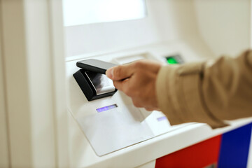 Close up of a hand with phone using ATM.