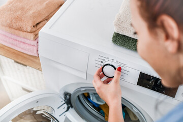 Detail of woman hand adjusting washing machine.