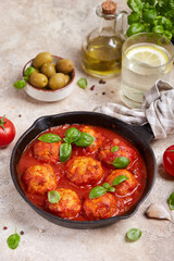 Chicken meatballs from minced meat baked with tomato sauce and herbs, served with basil leaves. Healthy dinner for the family. 