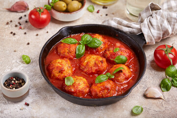 Chicken meatballs from minced meat baked with tomato sauce and herbs, served with basil leaves. Healthy dinner for the family. 